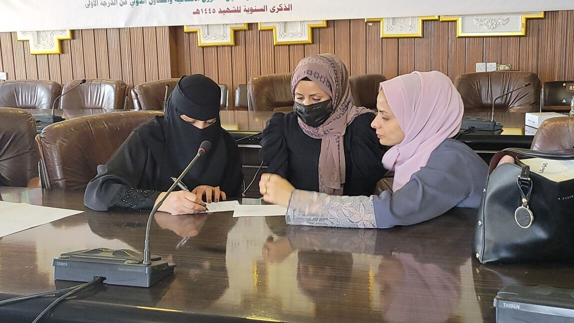 Three women at a conference table, one signing a document during a formal meeting in Yemen