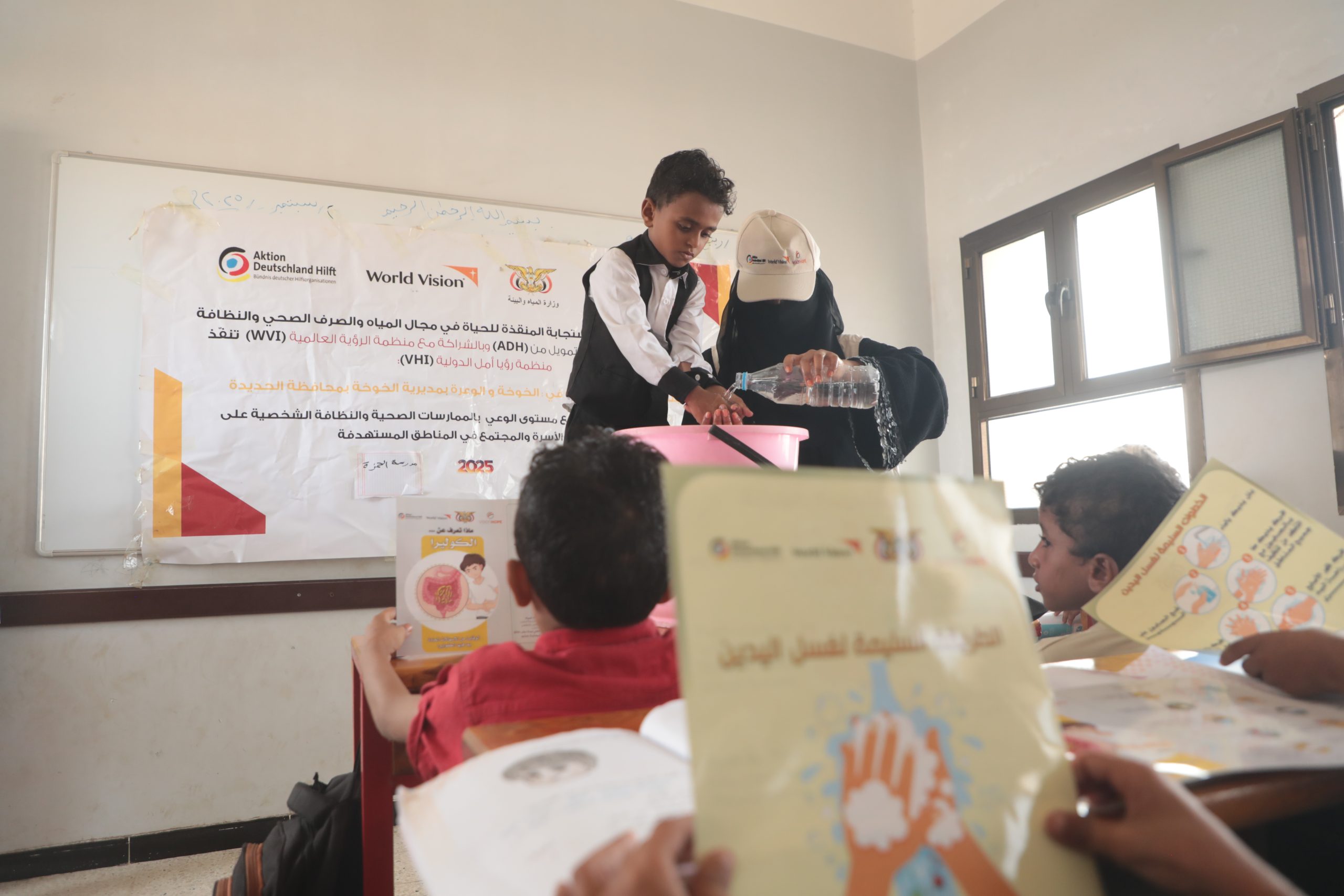 Facilitator demonstrating handwashing to a schoolboy during a cholera-prevention hygiene session in Yemen