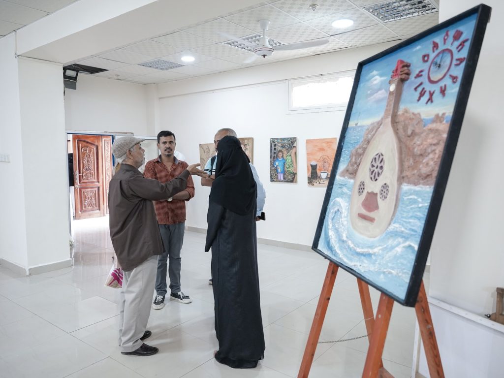 Visitors discussing artwork at a peacebuilding art exhibition in Aden, Yemen