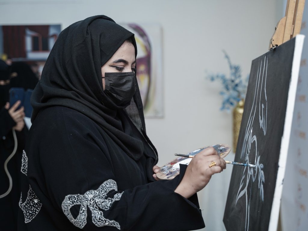 Woman painting during a creative workshop at an art exhibition in Aden, Yemen
