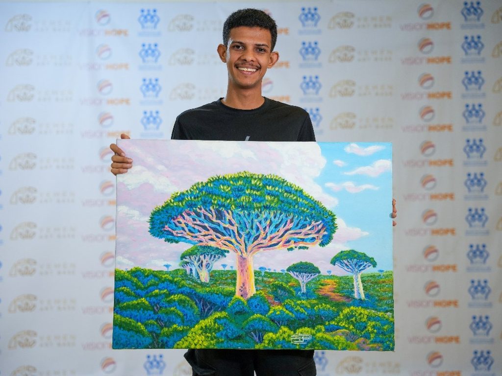 Young artist holding his painting at an art exhibition in Aden, Yemen