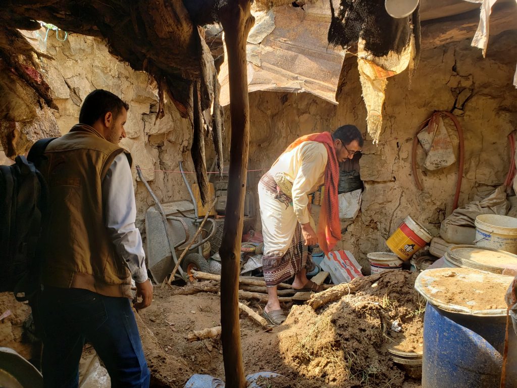 Aid workers assessing a family's makeshift stone shelter during disaster relief verification in Mahal Khabt, Yemen