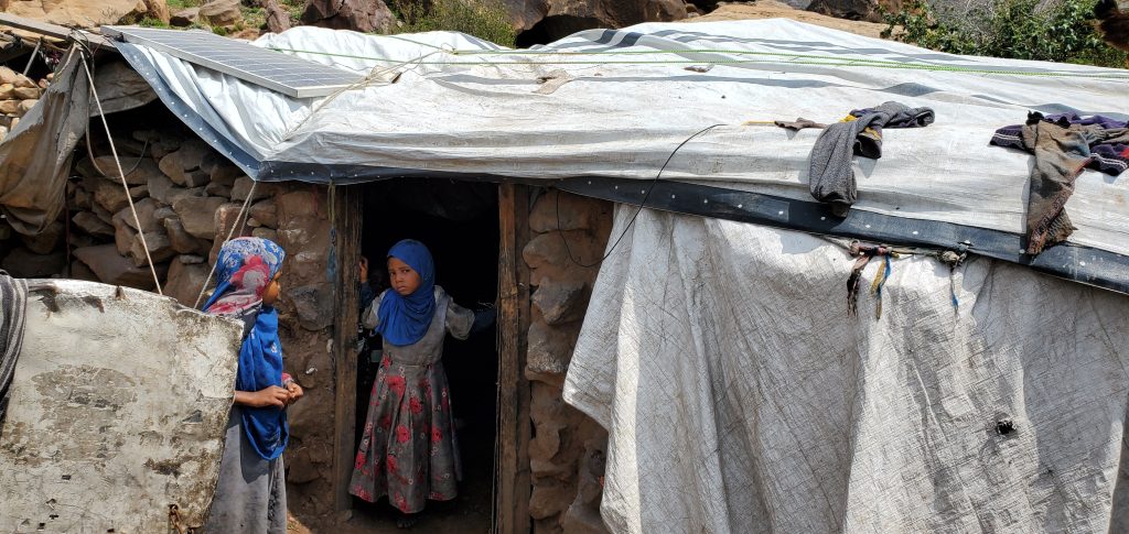 Two girls at the doorway of a stone shelter during a household verification visit in Shibam, Yemen