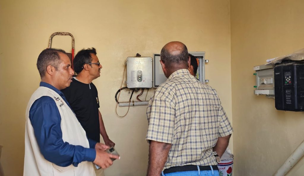 Engineers inspecting solar pump control equipment at a water station in Yemen