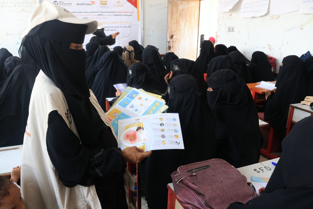Vision Hope facilitator leading a women's hygiene awareness session using illustrated educational materials in Yemen