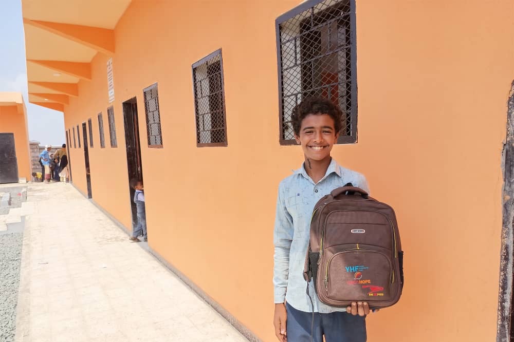 Smiling boy holding a school backpack provided by Vision Hope in Yemen