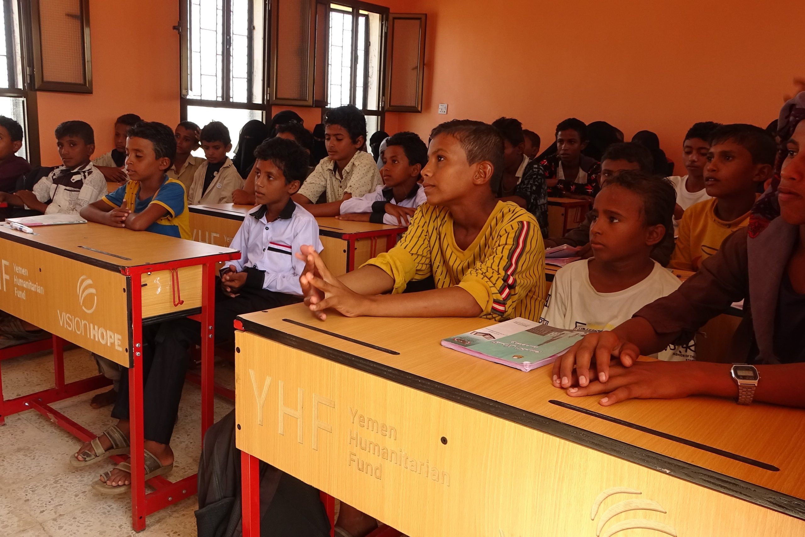 Students sitting at Vision Hope and Yemen Humanitarian Fund branded desks in a Yemen classroom