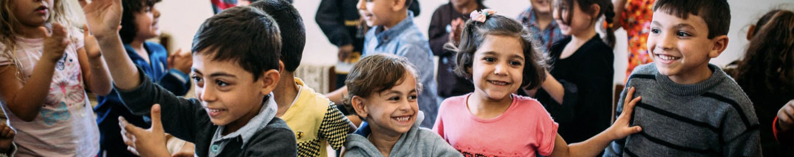 A group of smiling and laughing children sitting and playing together in a bright indoor setting