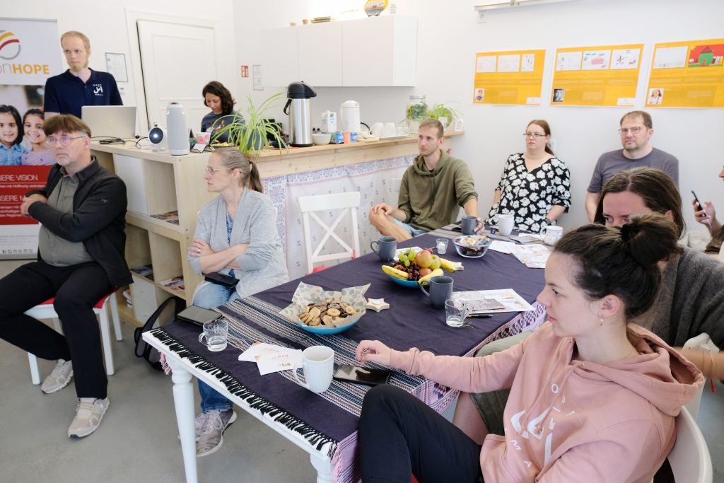 Team members and visitors gathered around a table at the Vision Hope Berlin office during a members' meeting