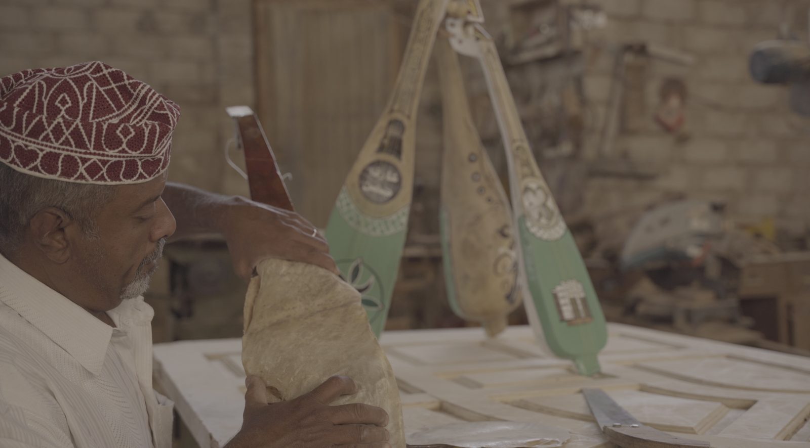 Jemenitischer Handwerker mit besticktem Käppi baut eine traditionelle Oud (Laute) in seiner Werkstatt