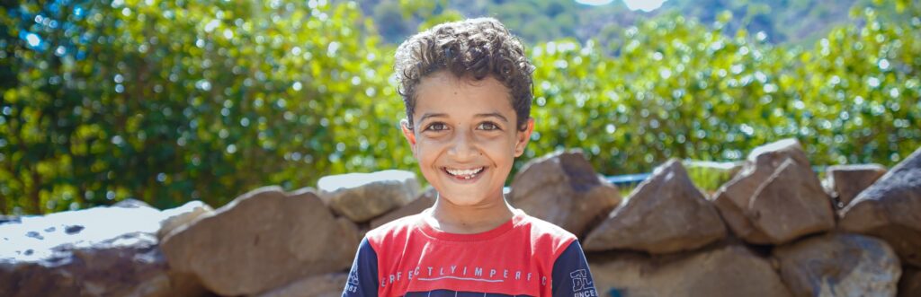 Smiling boy outdoors, representing the communities supported by Vision Hope's work