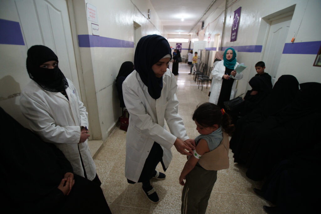 Medical staff providing healthcare support to a child at a community clinic in Syria